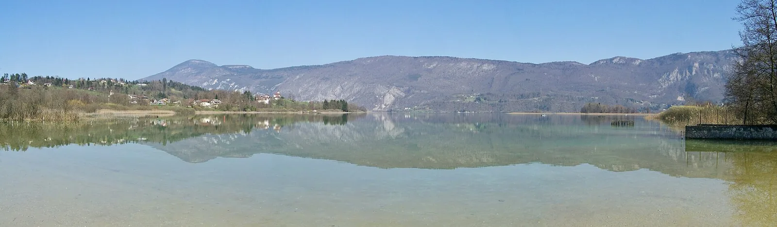 Panorama du lac d'Aiguebelette en Savoie, eaux vertes bordées de collines boisées et de montagnes — alternative moins fréquentée aux grands lacs alpins.