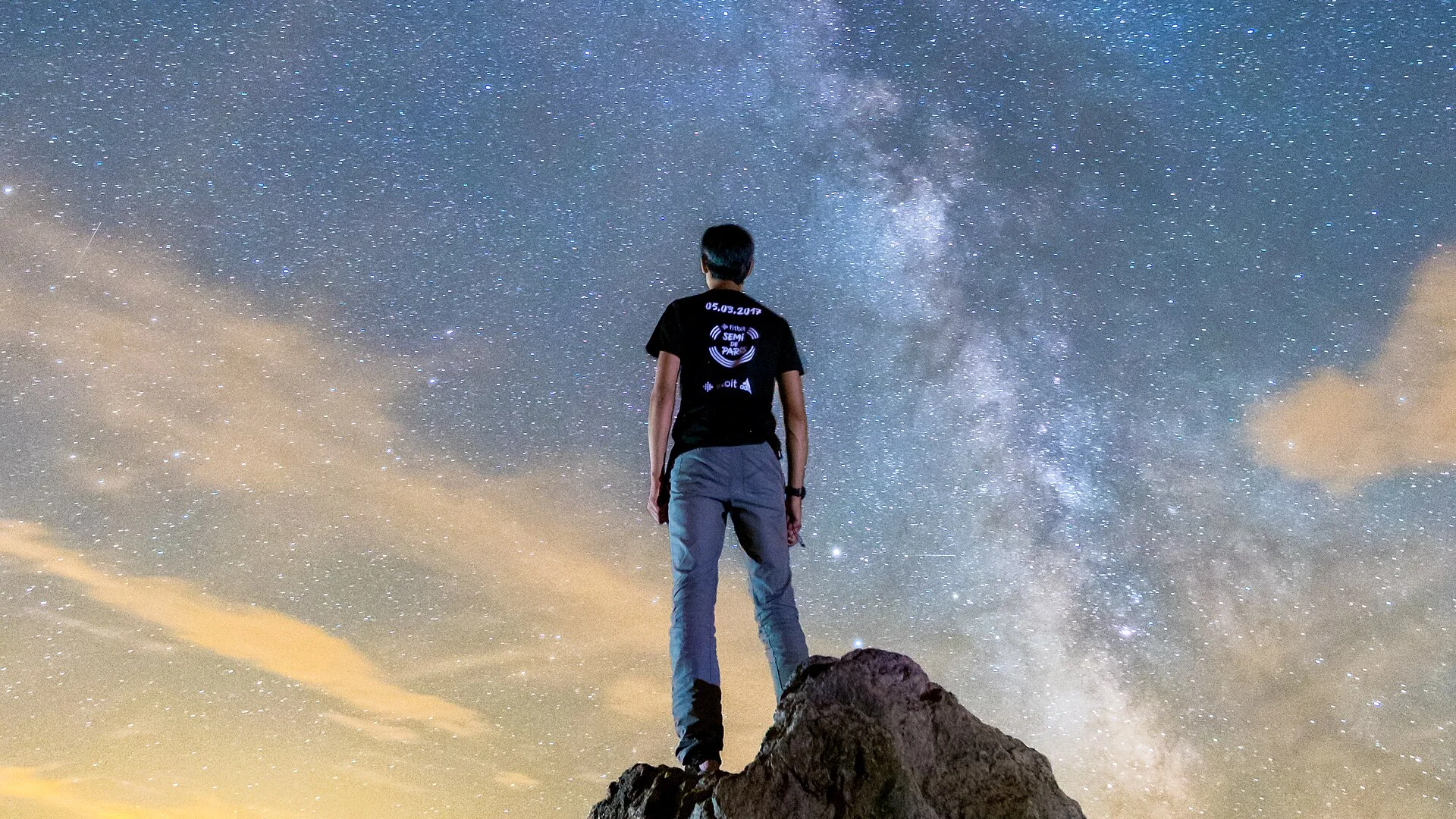 Voyageur debout sur un rocher, contemplant la Voie lactée dans un ciel étoilé au-dessus du Morvan, en France — scène d'observation nocturne en pleine nature.