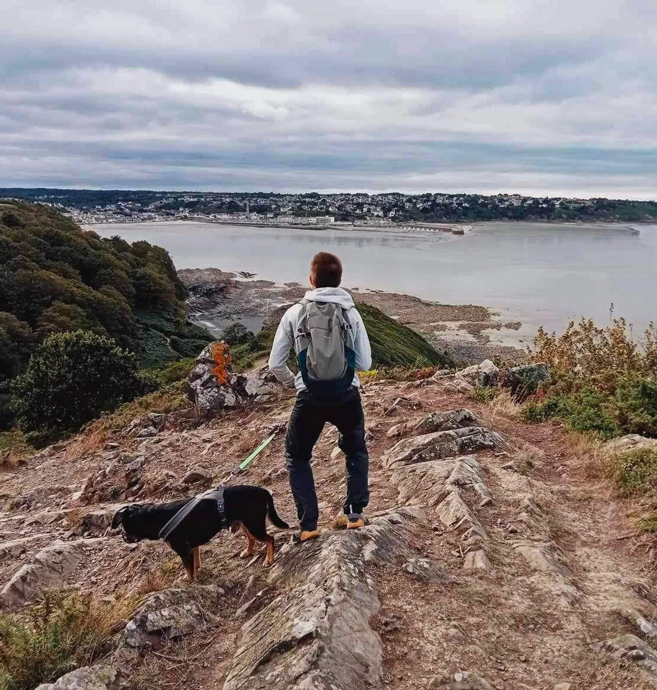 Voyageur de dos face à un paysage côtier en France, illustrant le choix d'une destination nature pour un séjour cohérent.