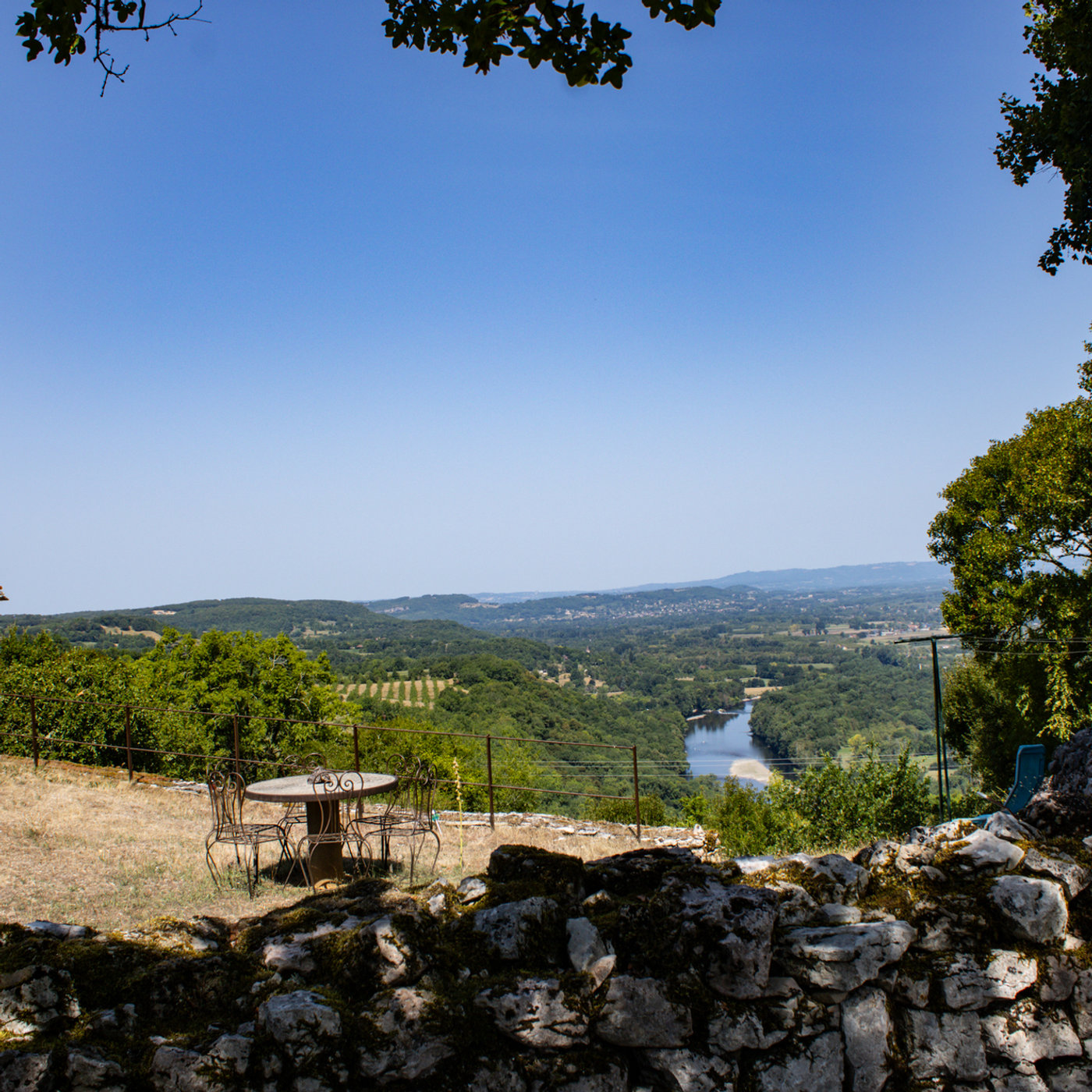 Vue panoramique sur la vallée de la Dordogne en Périgord : méandres de la rivière, forêts et villages nichés dans un paysage vallonné.