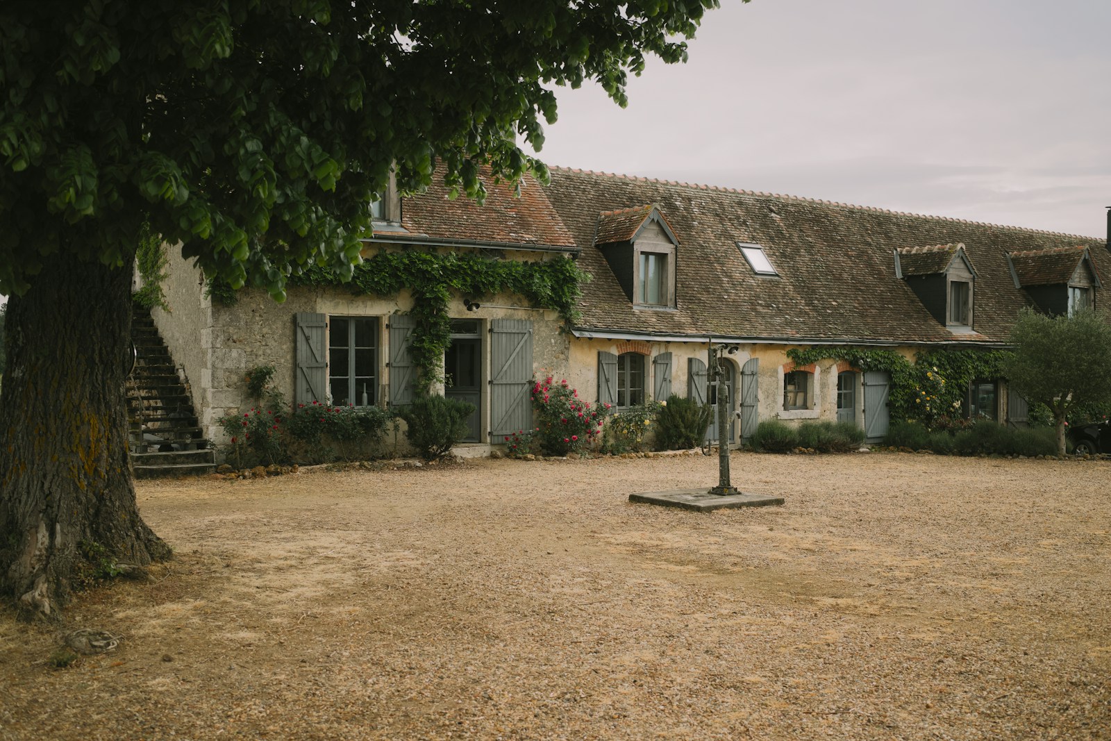 Ferme française traditionnelle en pierre avec grande cour rustique, ambiance paisible de campagne — vacances à la ferme accessibles et responsables.